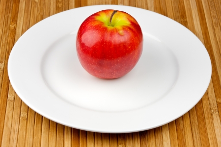 apple on a plate standing on a bamboo napkinの写真素材