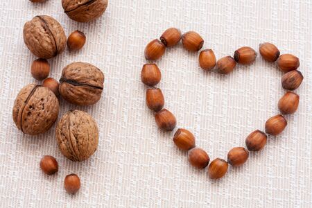 walnuts, hazelnuts on a wooden background in the form of heartの写真素材