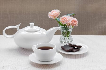 teapot, cup, roses, and chocolate on a plateの写真素材