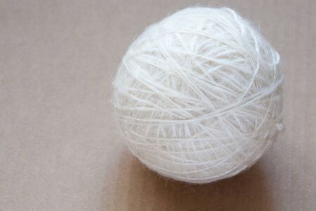 Ball of white wool yarn on cardboard backgroundの写真素材
