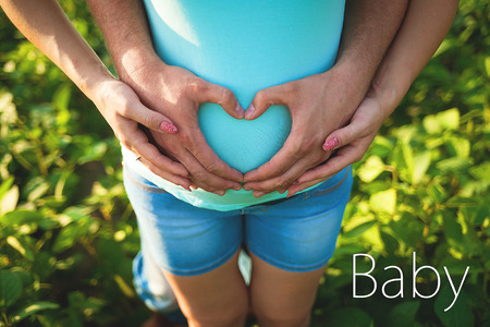 Mans hands embrace a belly of the pregnant woman.の写真素材