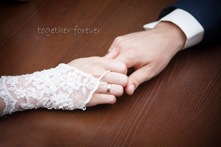 Bride and groom holding hands on wood background.の写真素材