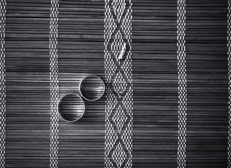 Two wedding rings on bamboo mat. Black and white photo.の写真素材