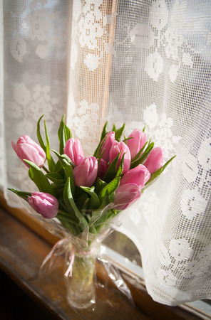 Beautiful white Roses in a glass vase near windowの写真素材