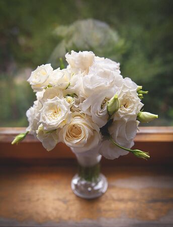 Beautiful white Roses in a glass vase near windowの写真素材