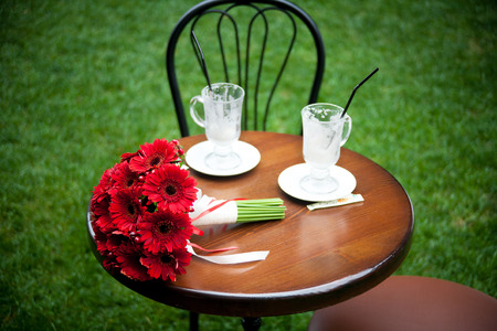 red bridal bouquet and cappuccino, coffee cup on tableの写真素材
