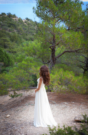 beautiful girl wearing white flowy dress in forest. Back viewの写真素材