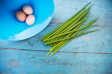 Natural white eggs in a blue bowl and Spring onions over old blue wooden table.の写真素材
