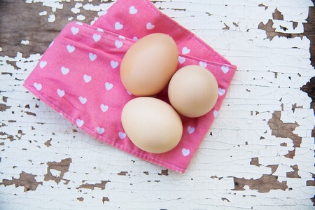 Eggs on pink tablecloth over old cracky white wooden background. Top viewの写真素材