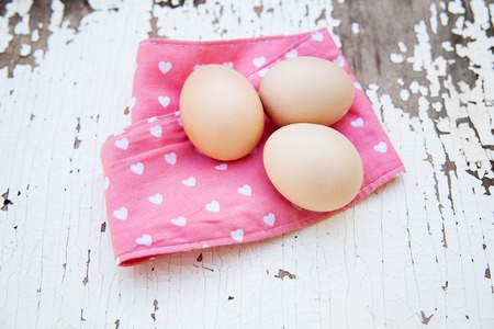 Eggs on pink tablecloth over vintage cracky white wooden background. Top viewの写真素材