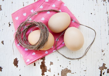 Eggs on pink tablecloth and old rope over vintage cracky white wooden background. Top viewの写真素材
