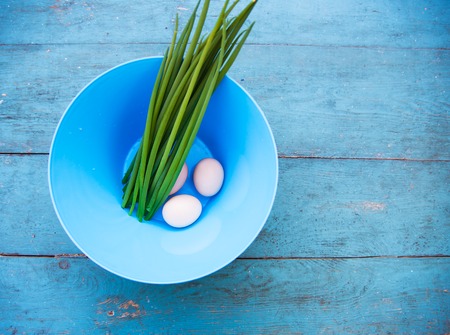 Natural white eggs in a blue bowl and Spring onions over dingy  blue wooden table. Top viewの写真素材