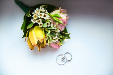 rings and flowers. Groom's boutonniere closeup. Wedding boutonniere of roses.の写真素材