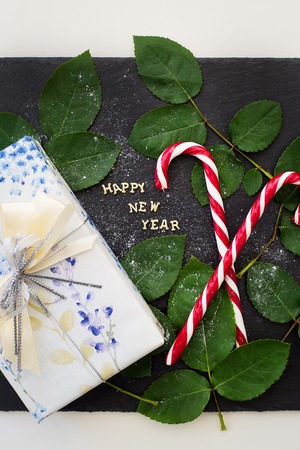 inscription of new year on a black board with a nice gift and red candy