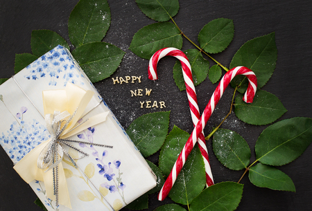 inscription of new year on a black board with a nice gift and red candyの写真素材