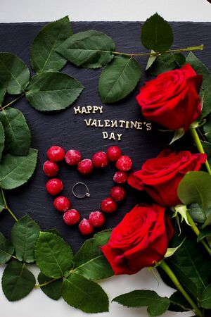 Happy Valentine inscription, cherries in a heart with red roses, rings, close-upの写真素材