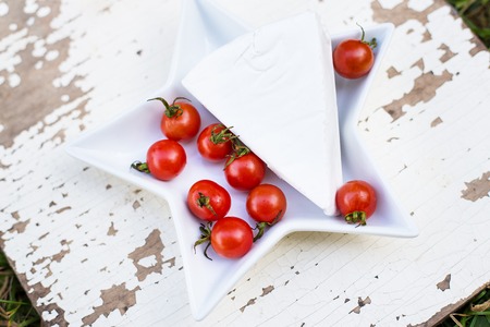 white plate with white cheese and fresh cherry tomatoes close-upの写真素材