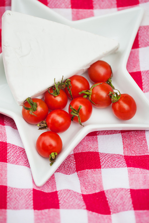 brie cheese and cherry tomatoes on a red tablecloth. close upの写真素材