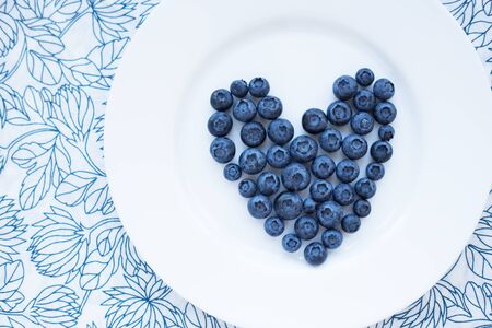 blueberries in a heart shape on a white plateの写真素材