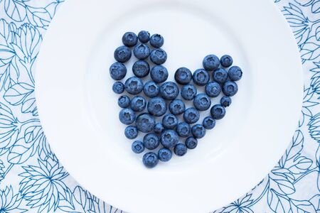 blueberries in a heart shape on a white plateの写真素材