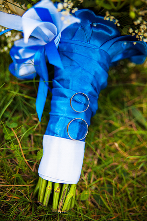 wedding rings and bridal bouquet lying on a green grassの写真素材