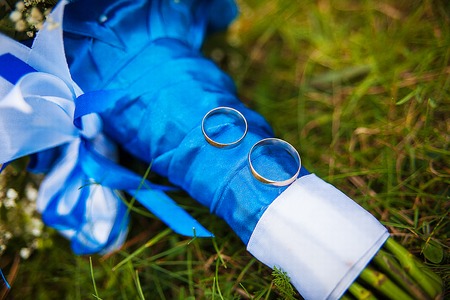 wedding rings and bridal bouquet lying on a green grassの写真素材