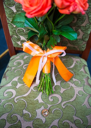 wedding bouquet with red flowers on a chair with a ringの写真素材