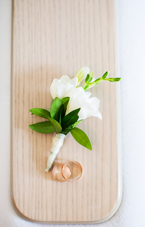 beautiful boutonniere and golden wedding rings on the tableの写真素材