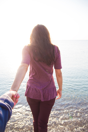 man holding the hand of a girl who stands with his back to the seaの写真素材