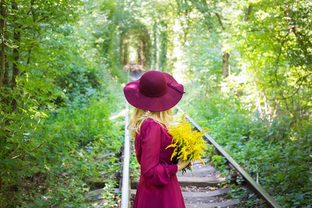 girl in a hat with a bouquet of yellow flowersの写真素材