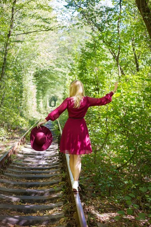 The girl was standing on the tracks in the forest with cherry hat. Tunnel of love - Ukraineの写真素材