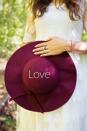 A girl in a white dress with cherry hat in the woods inscription loveの写真素材