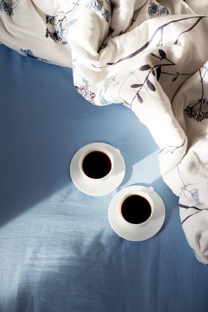 two cups of coffee in bed, sunlightの写真素材