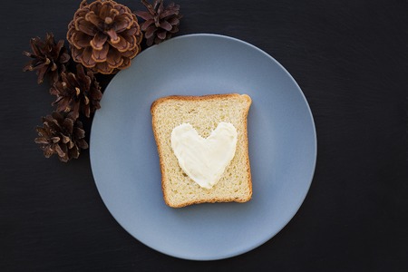 sandwich for breakfast in the form of heart with cheese on a blue plate and black background with conesの写真素材