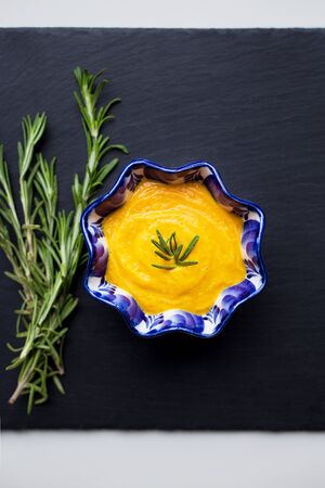 delicious pumpkin cream soup and black background with rosemaryの写真素材