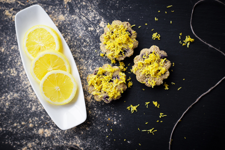 lemon cupcakes on a black background and a lemon on a plateの写真素材