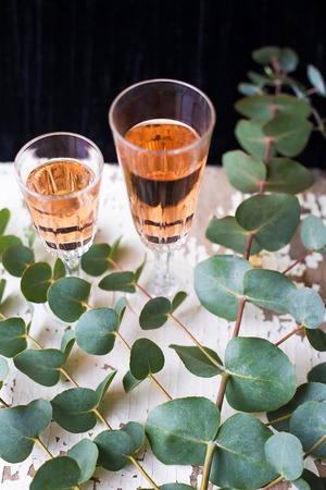 eucalyptus branches on an old table with a glass of rose wineの写真素材
