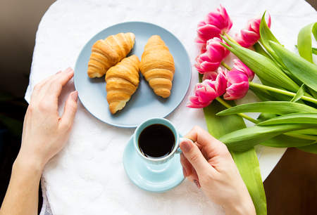 Girl with croissants and coffee, a bouquet of pink tulips, happy morning.の写真素材