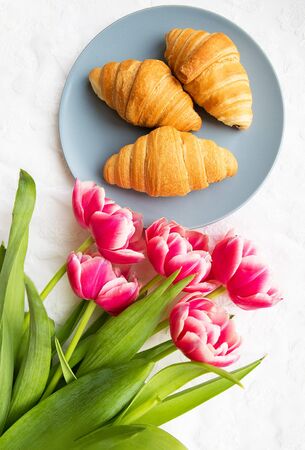croissants on the background of laces on a white background with a bouquet of pink tulips.の写真素材