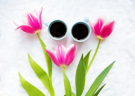 two cups of coffee and a bouquet of pink tulips.の写真素材