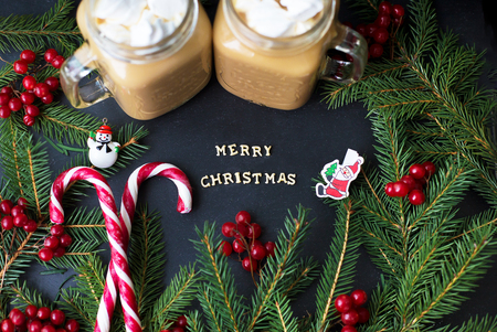 Candies and cocoa with marshmallows on a black background with the branches of trees. The inscription Merry Christmas.の写真素材