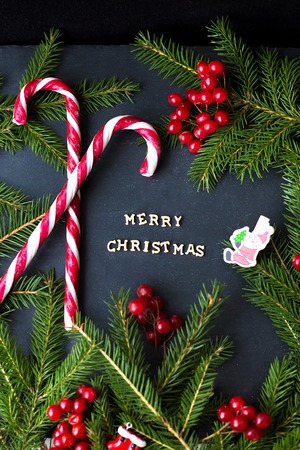 Candy on black background with branches of trees. The inscription Merry Christmas.の写真素材