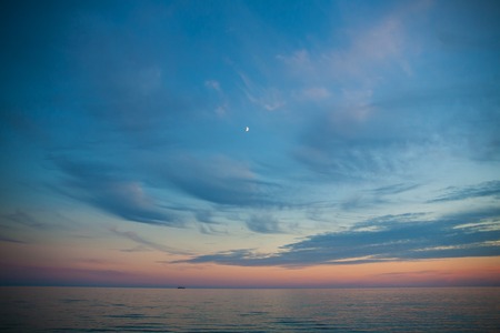 Sea and sky at sunset. Beautiful landscape. month in the sky and boat in the distanceの写真素材