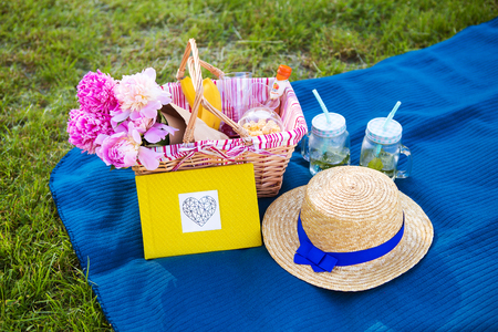 Beautiful flowers in a basket and yellow album lie on the grass-bright picnicの写真素材