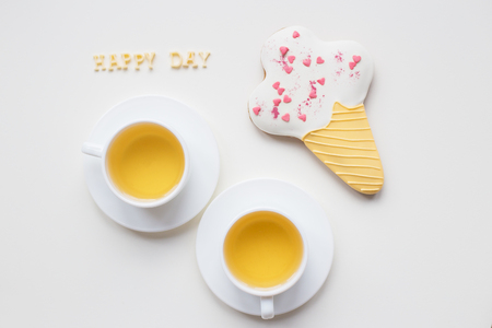 two cups of coffee on a table with cookies in the form of ice, inscription happy dayの写真素材