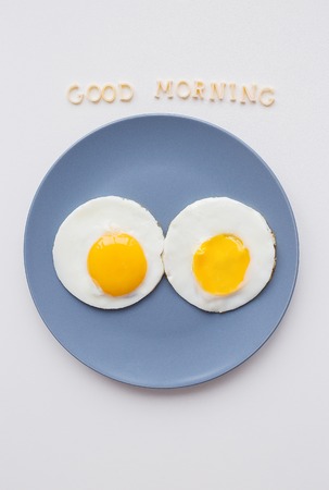 two eggs on a plate and a yellow napkin, inscription Good Morningの写真素材