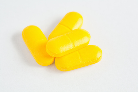 bunch of yellow capsules on white backgroundの写真素材