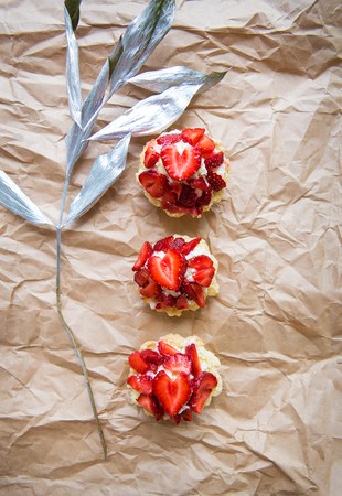 Beautiful cupcakes with strawberries along with a branch on kraft paper.の写真素材