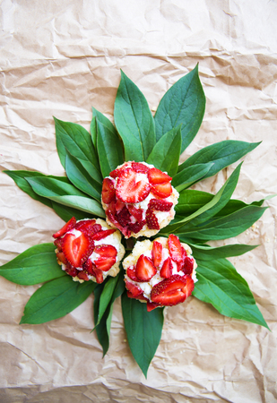Beautiful and bright cupcakes with strawberries lie on green leaves.の写真素材