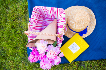 Beautiful flowers in a basket and yellow album lie on the grass-bright picnicの写真素材
